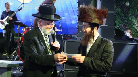הרב שלמה סוויסה שליט'א מעניק את המלגה לכותב חיבור.jpeg